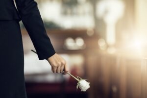 A mourner brings a white rose to a loved one’s grave after their wrongful death.