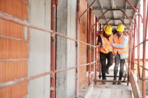 A construction worker helps an injured colleague go to safety. A Beverly Hills workers' compensation lawyer will help you claim benefits.
