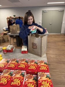 A happy volunteer creates a meal kit for the holidays.
