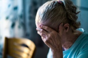 An elderly woman appears sad and wonders, “What are the signs of nursing home abuse?”
