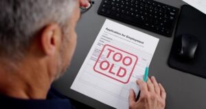 A man looking at proof of discrimination in the workplace in the form of a paper that says he is too old to work